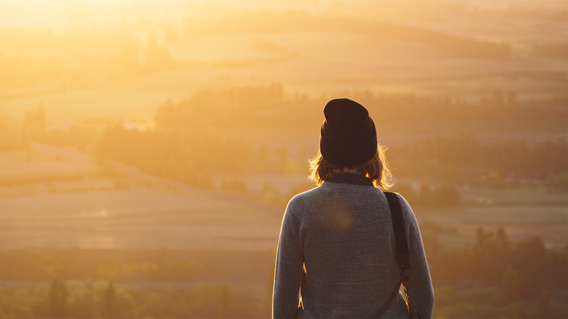 A woman stands at the top of Mt. Iron in Wanaka, New Zealand