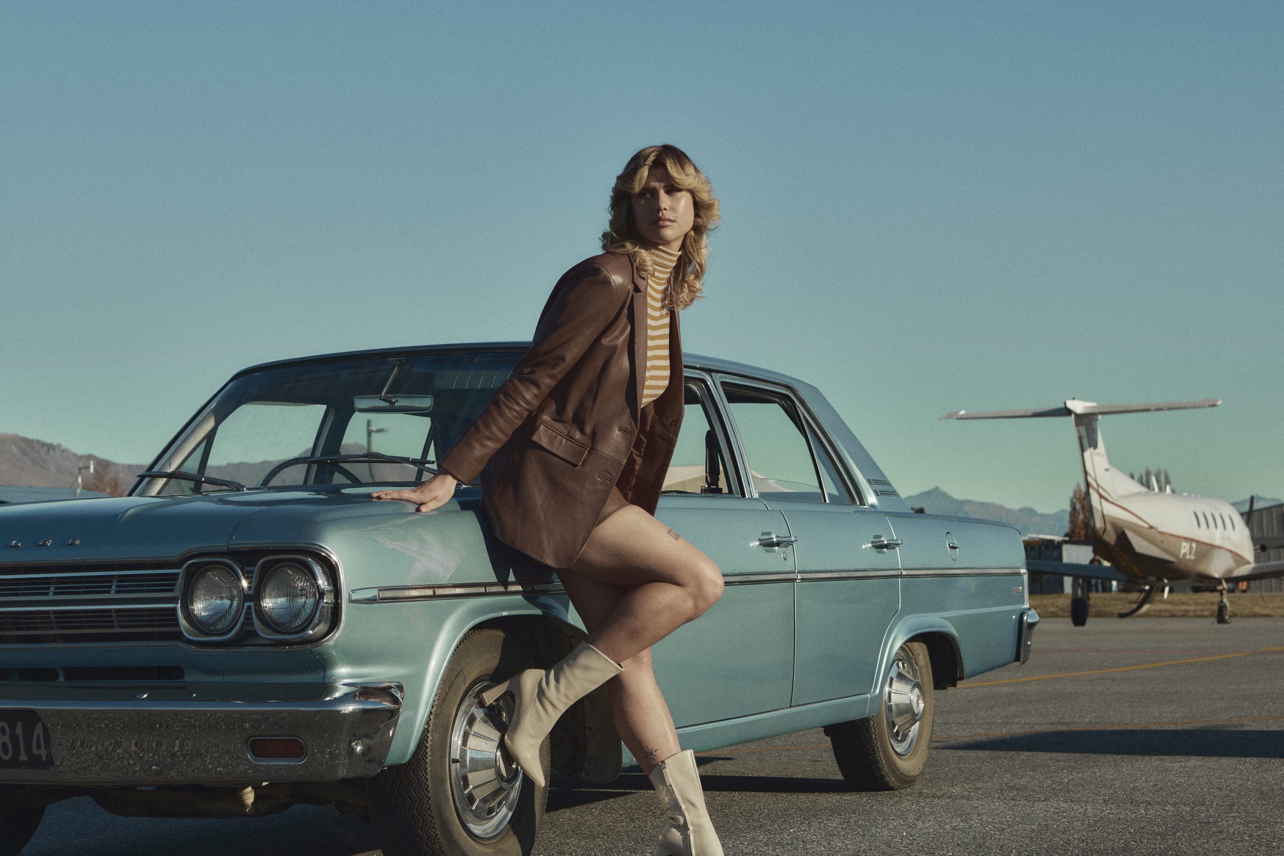 Girl leaning up against a car on an airport runway