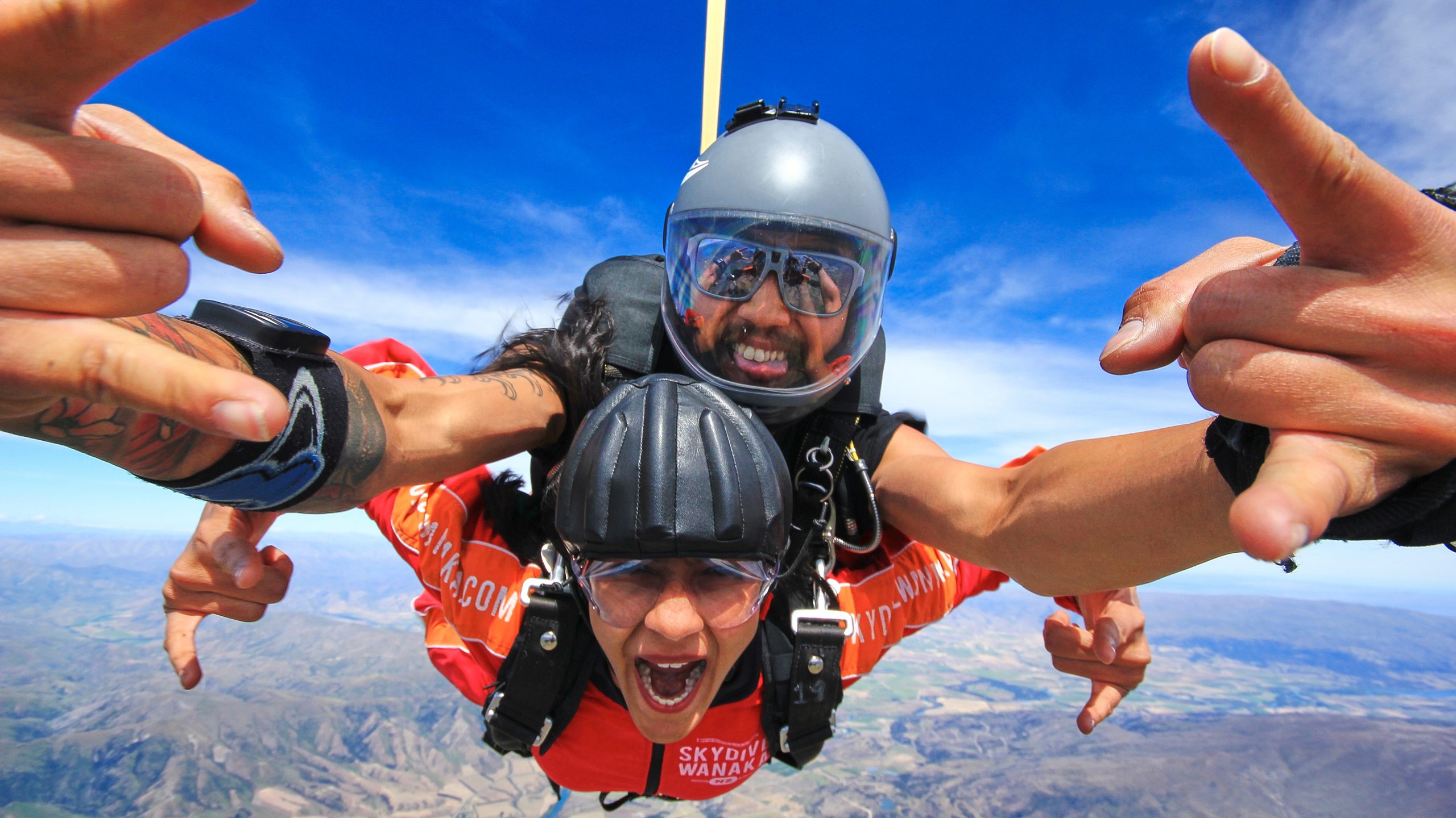 Adrenaline-filled tandem skydive over Wānaka with clear blue skies and scenic landscapes below.