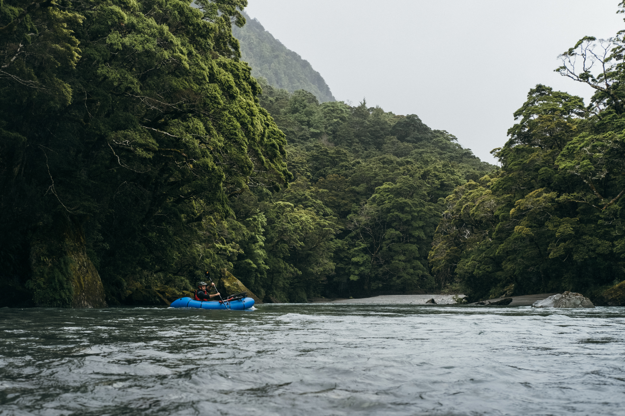 A man packrafting down a river in Makarora New Zealand